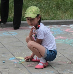 Девочка рисует на асфальте